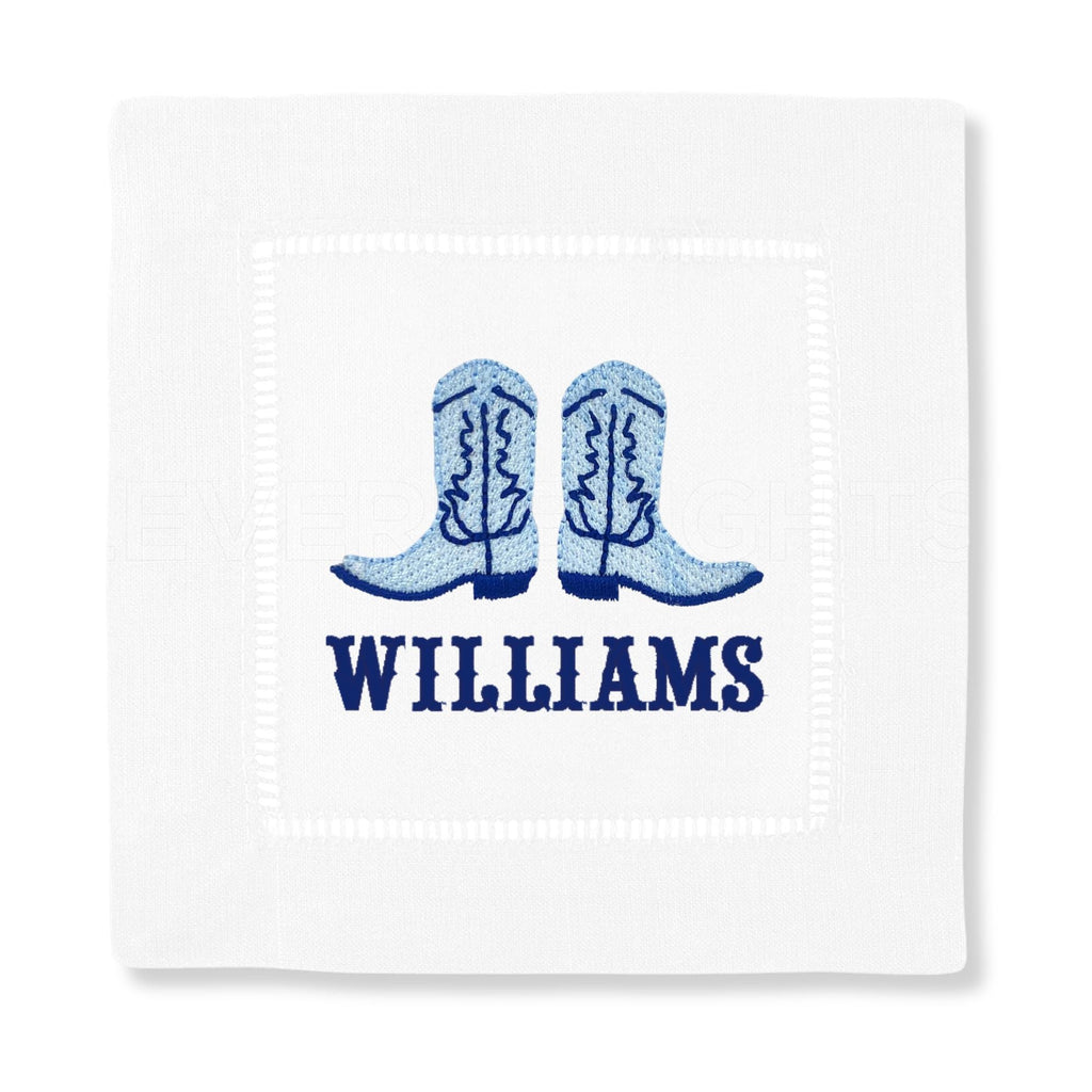 An embroidered cocktail napkin with a pair of blue cowboy boots and a custom name.