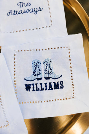 An embroidered cocktail napkin with cowboy boots and last name