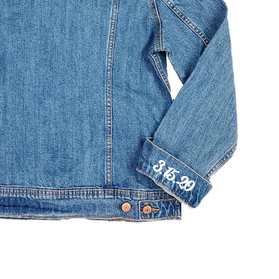 A jean jacket sleeve lies face up to show the custom date printed onto the sleeve.