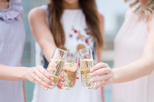 Three women in a bridal party cheers their custom champagne flutes.