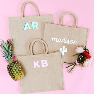 Some jute totes lay out to show some of the different personalization options.