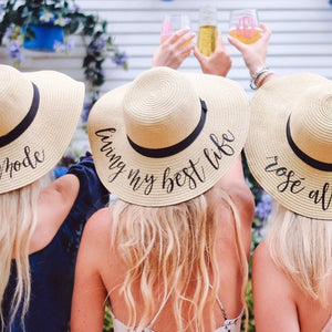 Three blondes toast while wearing customized beach hats