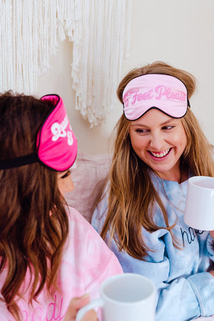 Two girls wear customized pink sleep masks on their heads.