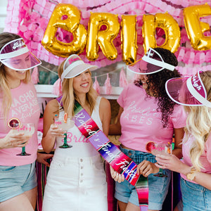 A bride shows off her custom sash to her bridal party