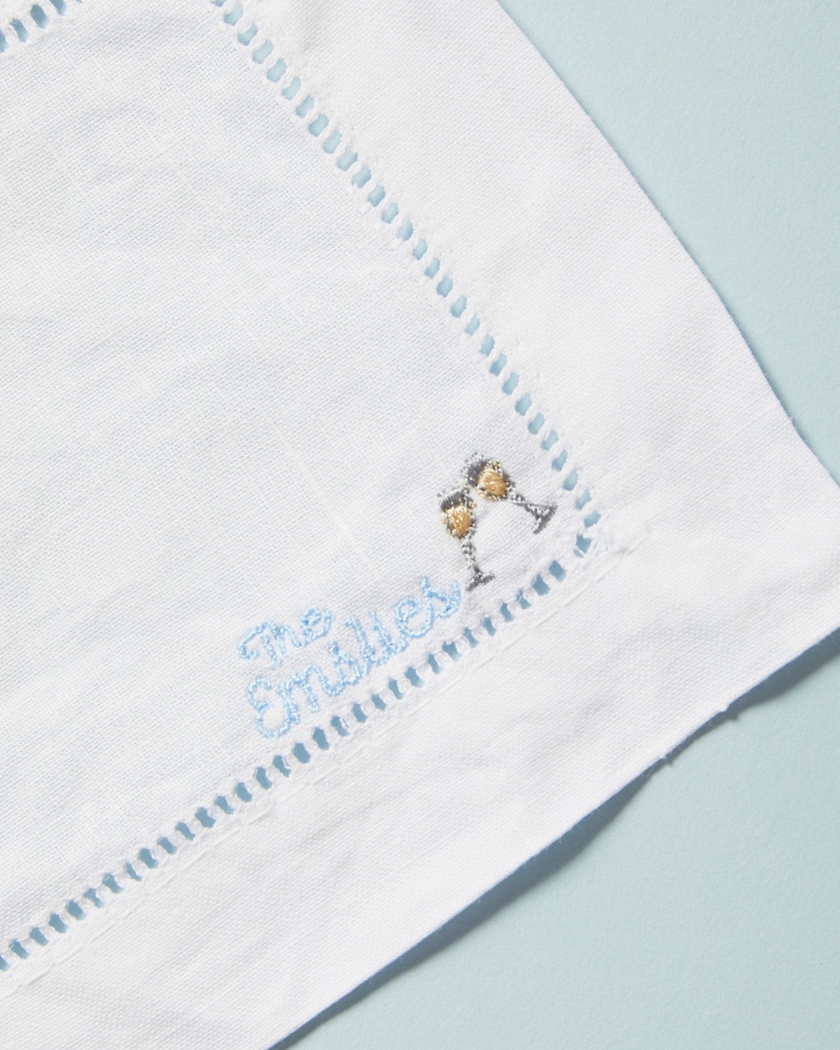 A cocktail napkin with a custom embroidered name and cocktail motif. 