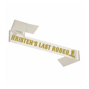 A white sash customized to read "Kristen's Last Rode" with a boot icon