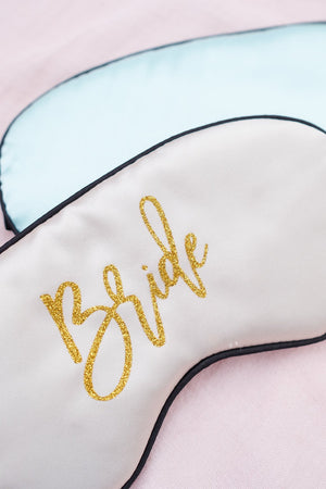 A light pink sleep mask is customized with gold glitter font for a Bride.