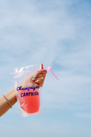 A person holds up a party pouch which is customized with "champagne campaign" in a purple font.