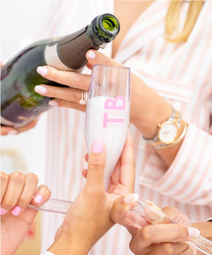 A person pours champagne into a pink monogrammed chambong