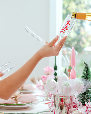A person fills a chambong with a custom name on it with champagne.
