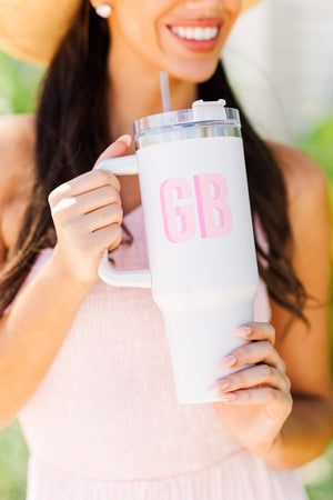 A woman holds a white tumbler with a "GB" monogrammed on the front