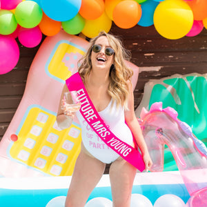 A woman in a swimsuit wears a hot pink, Future Mrs. sash