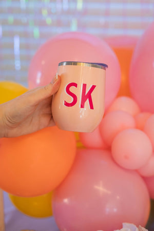 A wine tumbler is customized with a pink and white monogram 