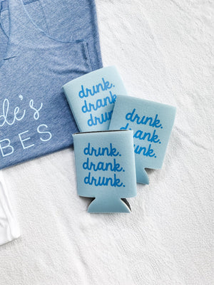 Three light blue koozies read "drink drank drunk" in a dark blue font
