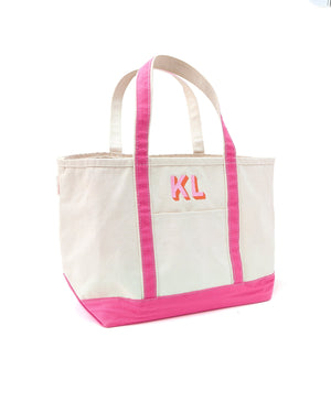 A pink canvas tote is personalized with a pink and orange embroidered monogram.