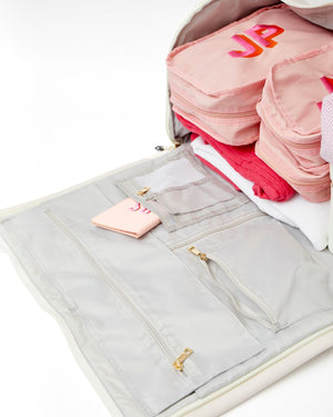 A pink passport holder is tucked into a grey pocket inside a garment bag.