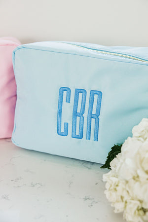 A light blue nylon pouch is customized with a blue monogram