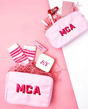 A set of pink nylon pouches with matching monograms are filled with pink items that are great for gifts.