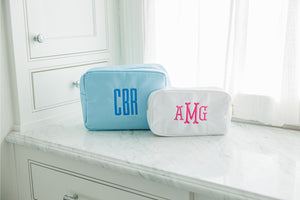 A light blue and white nylon pouch are embroidered with monograms.