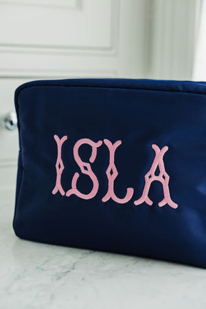 A navy nylon pouch is personalized with a name in a pink thread color.