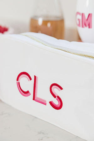 A white nylon pouch shows off a fun monogram with red, bubblegum pink, and light pink thread.