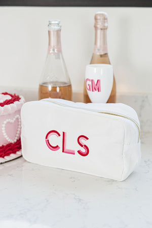 A white nylon pouch sits on a counter with some champagne and champagne flutes