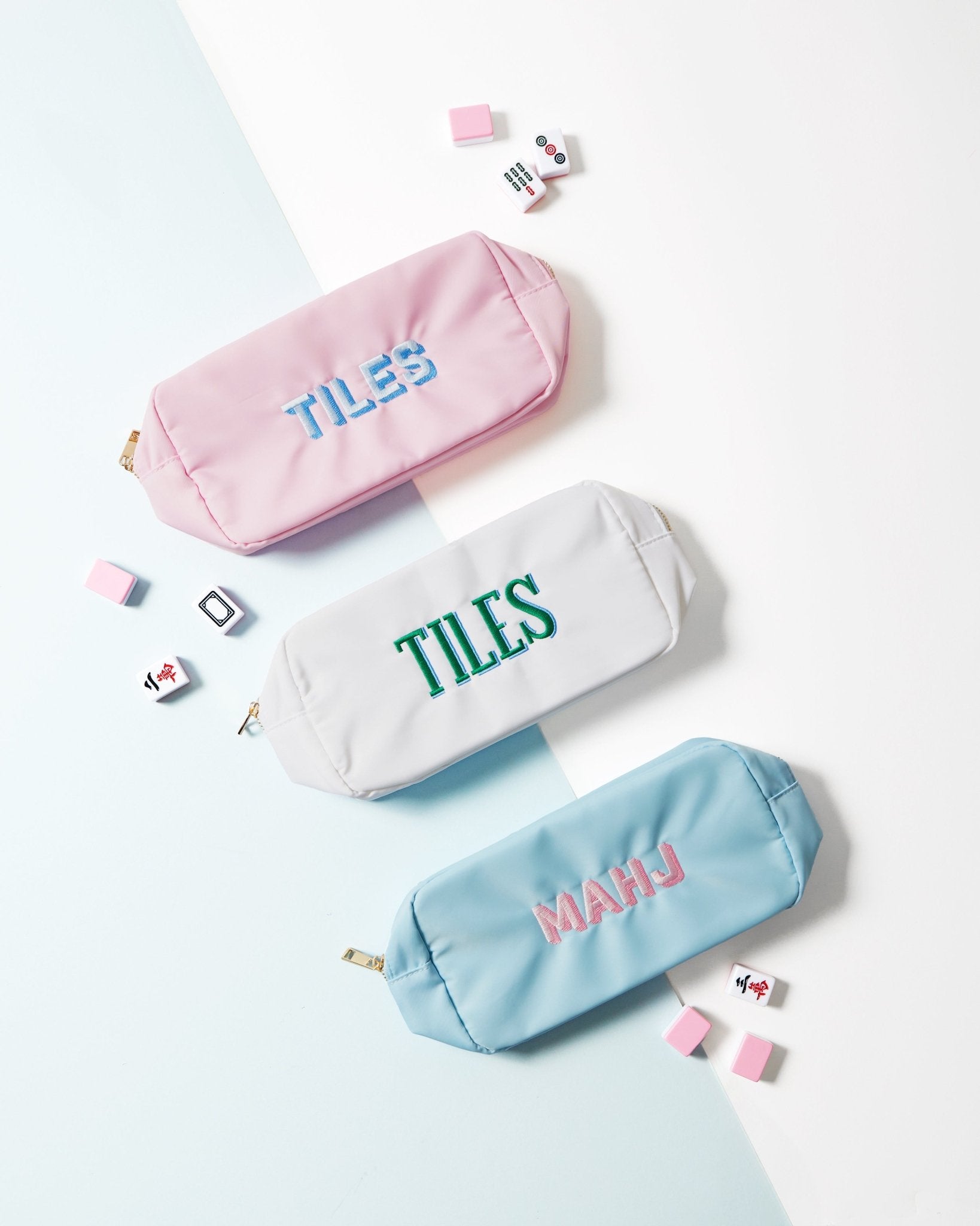 Three large, embroidered Mahjong inspired pouches in blue, white, and pink