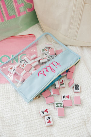 Mahjong tiles spill out of a blue clear pouch that reads "Tiles" on the front