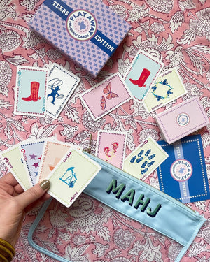 A person playing mahjong tiles next to a nylon clear pouch with the words "Mahj" embroidered on it