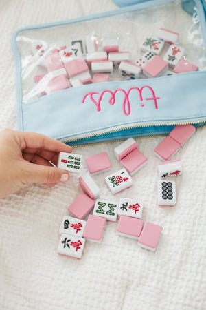 A woman pulls Mahjong tiles out of an embroidered blue pouch
