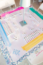 Mahjong tiles set up for four people, which are placed on a mat with an embroidered monogram on it 