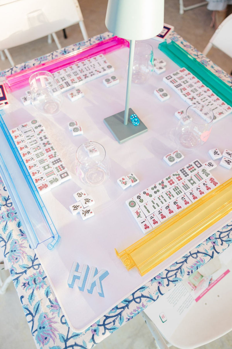 Mahjong tiles set up for four people, which are placed on a mat with an embroidered monogram on it 