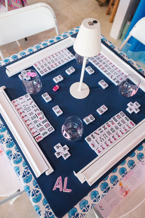 A pink, embroidered monogram on a blue mahjong tile mat