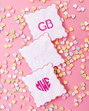 Three scalloped cocktail napkins are lined up to show their personalizations