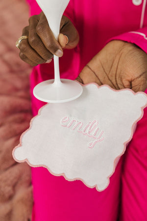 A woman holds a custom monogrammed champagne flute and a cocktail napkin