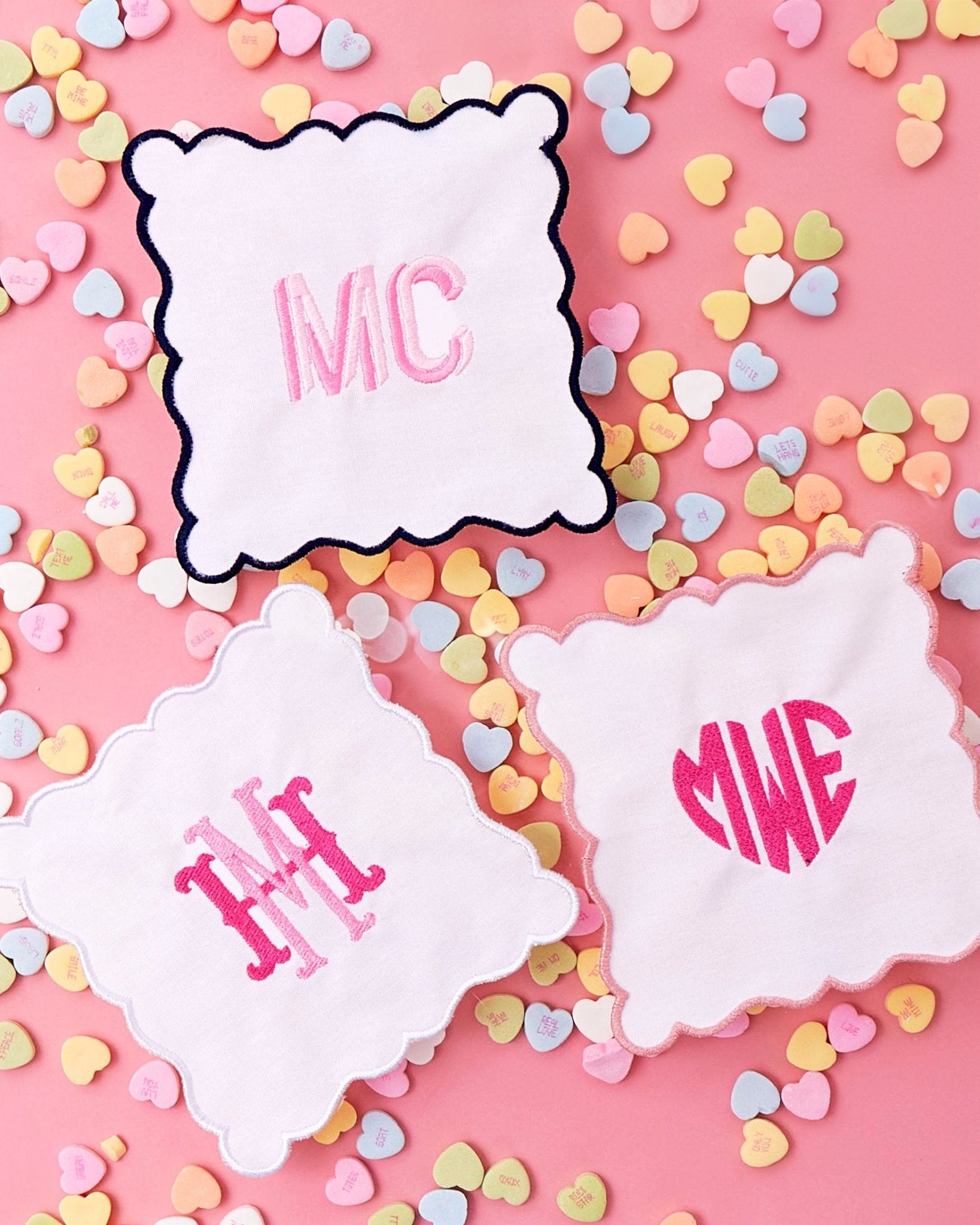 A pink and a white scalloped cocktail napkin are customized with monograms 