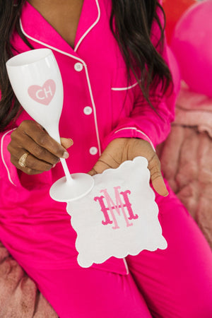 A woman holds a custom monogrammed champagne flute and a cocktail napkin