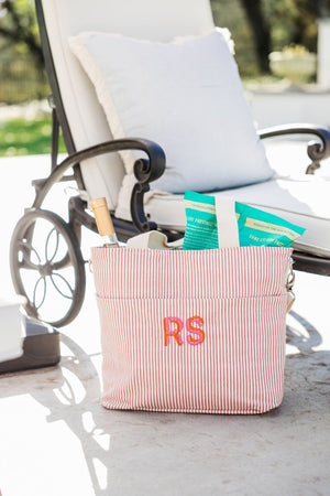 A pink cooler bag is customized with a pink and orange monogram.