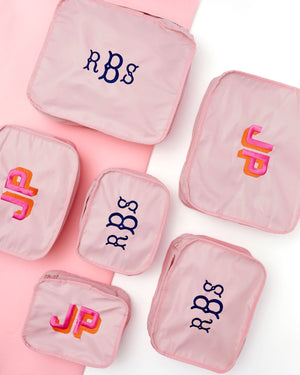 An array of pink packing cubes are embroidered with custom monograms.