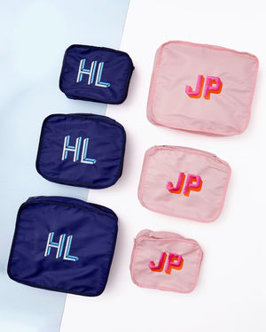 An array of navy and pink packing cubes are embroidered with custom monograms.