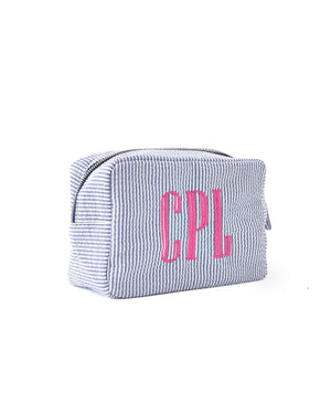 A navy seersucker pouch is customized with a pink embroidered monogram.