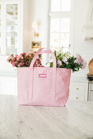 A pink tote bag is filled with a bouquet of flowers on a kitchen counter.