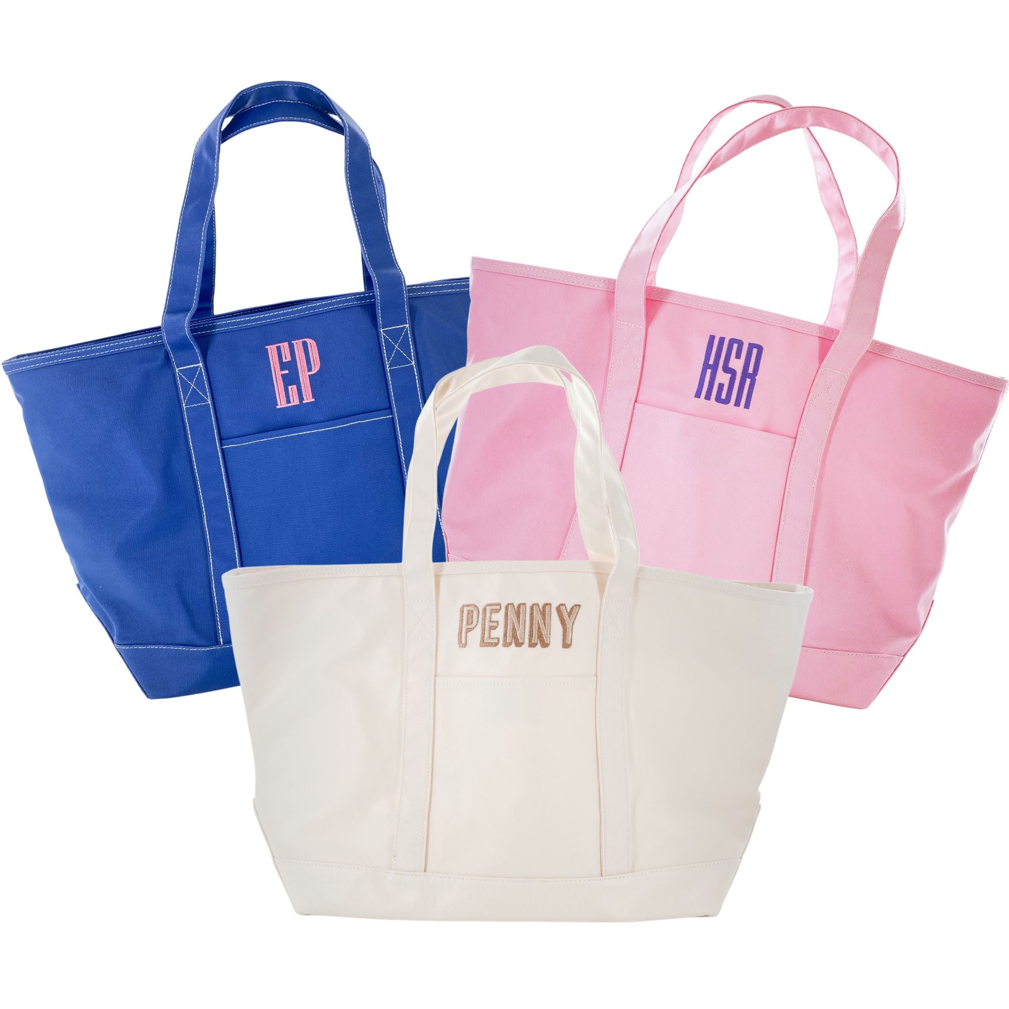 A cream, pink, and blue tote are personalized with embroidered monograms and names.