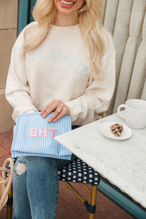A blonde reaches for an item in her blue embroidered roadie pouch