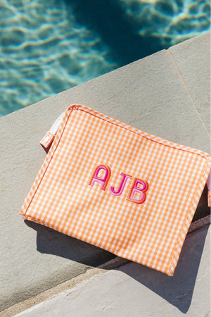 An orange roadie is customized with a pink monogram by the pool.