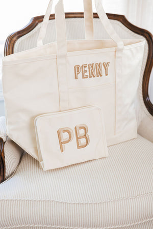 A white coated canvas and a white roadie are personalized with beige and tan embroidery designs.