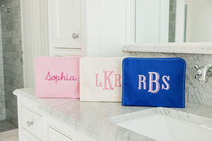 A group of solid colored roadies are monogrammed and placed on a bathroom counter.