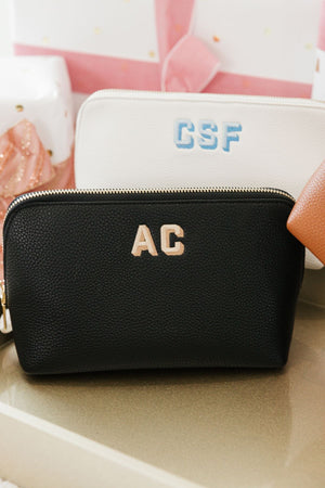A black and a white leather pouch are embroidered with different colored monograms .