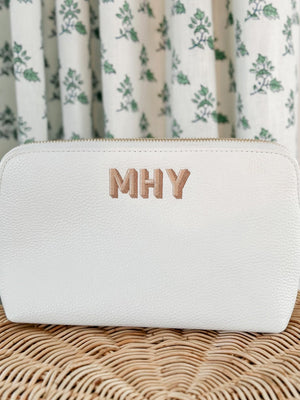 An embroidered leather pouch in a white color with the monogram "MHY"