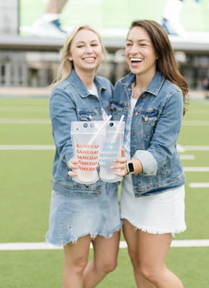 Two girls laugh as they hold up their gameday party pouches.